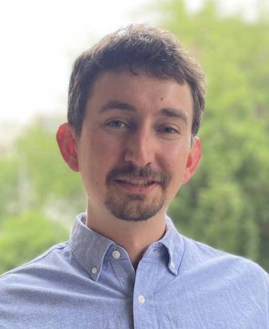 A headshot of LTI researcher Daniel Fried. He is smiling and wearing a blue oxford shirt.