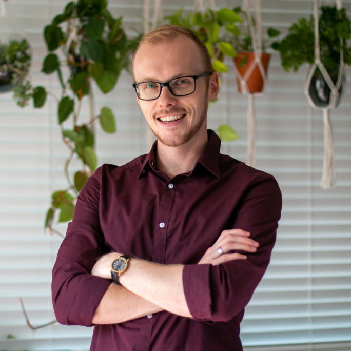 A headshot of Maarten Sap. He is wearing a purple dress shirt and smiling with his arms crossed.