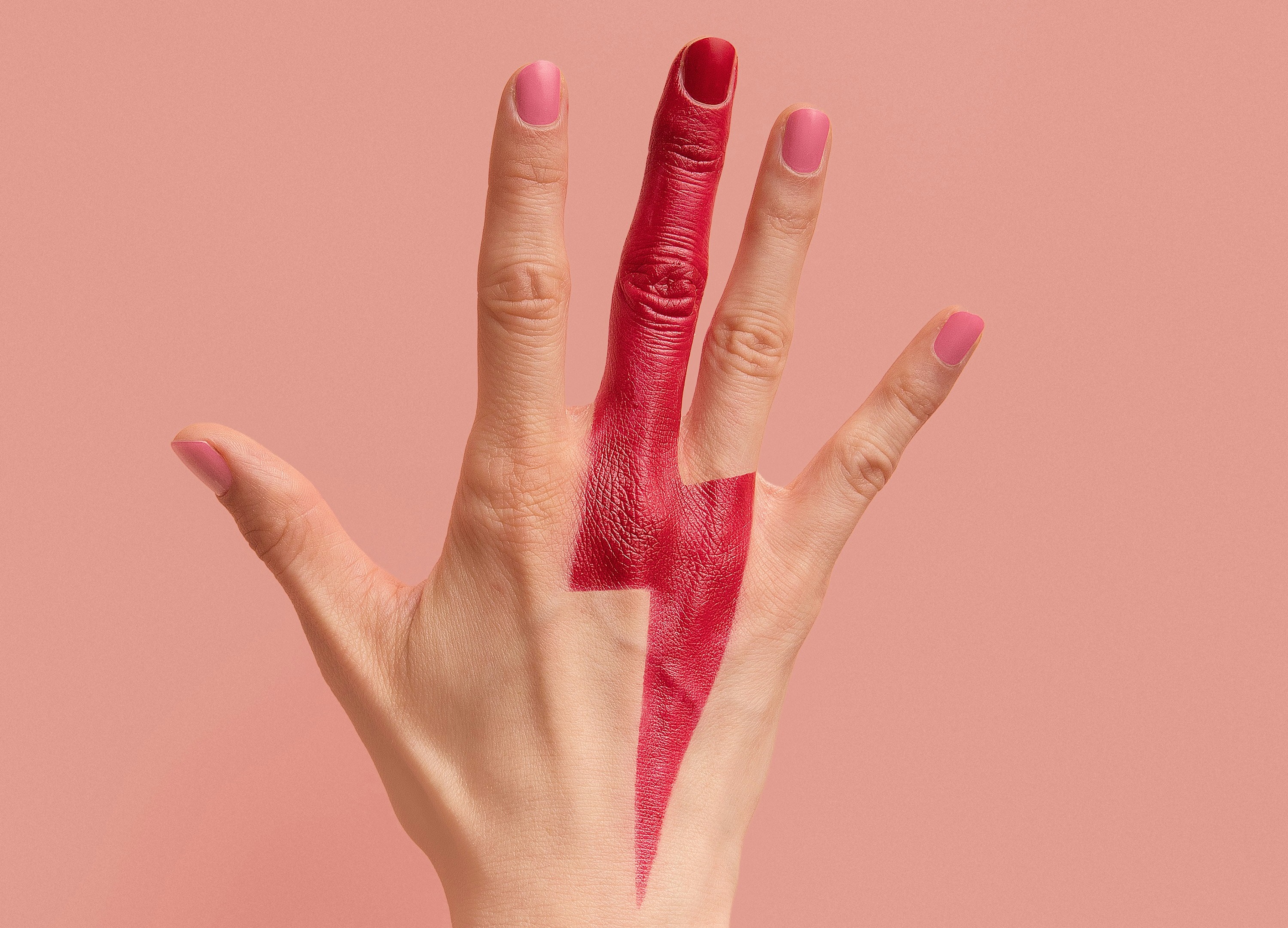 A hand with fingers outstretched, pink nail polish, and the middle finger painted red, which becomes a red lighning bolt on the back of the hand